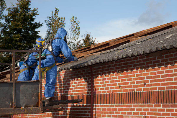 Workers in protective gear removing asbestos